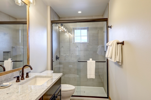 新的经典浴室内饰，带玻璃和陶瓷瓷砖，步入式淋浴和灰色墙壁和白色毛巾