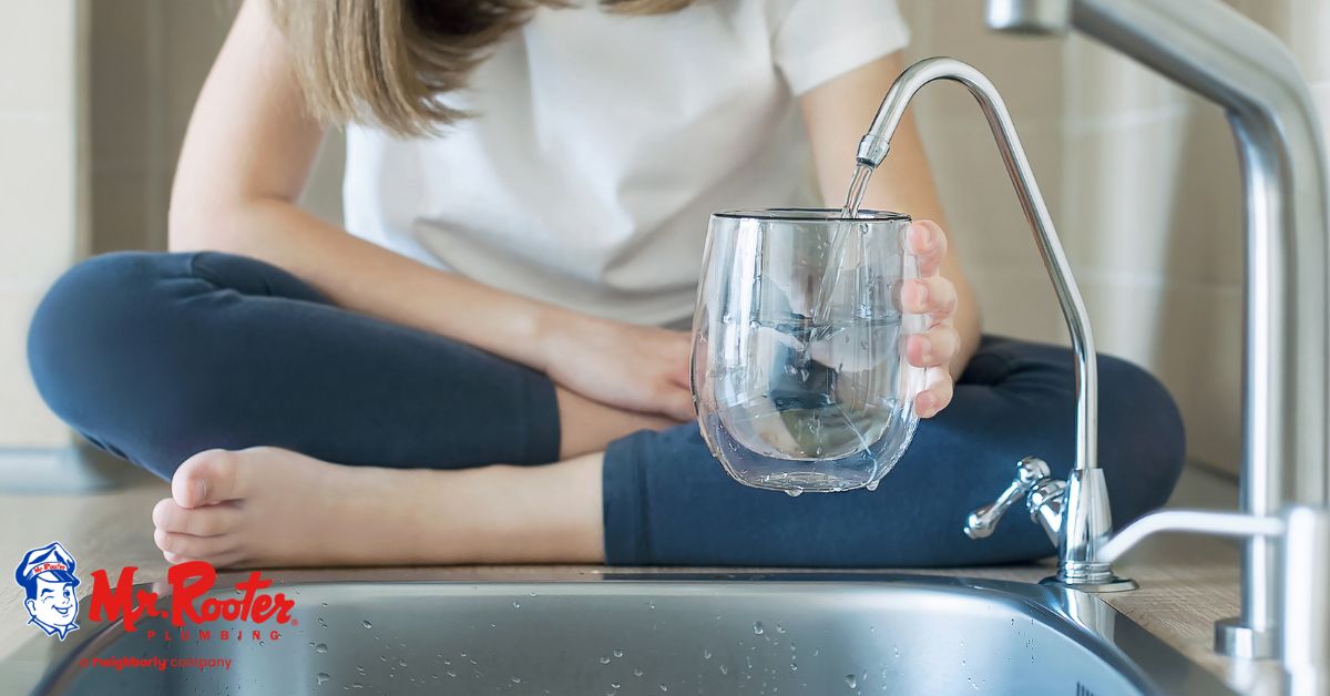 girl sitting on counter filling up water from filter