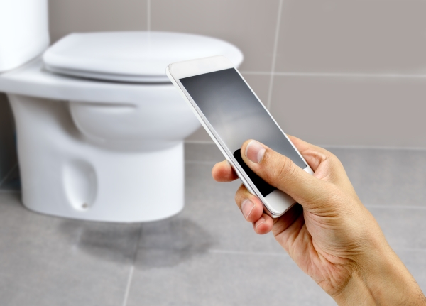 Person using a cell phone to take a picture of a leaking toilet